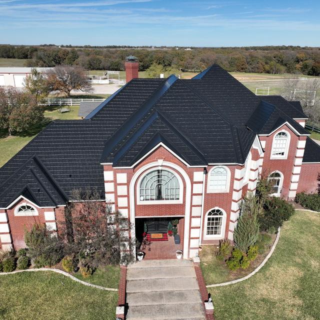 A stately brick home with EDCO’s ArrowLine Black Metal Roofing, providing a sleek, durable contrast to the red brick exterior.