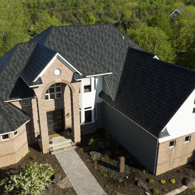 A brick home with Infiniti Textured Shake Metal Roofing in Obsidian, offering a sleek and durable contrast to the home’s classic design.