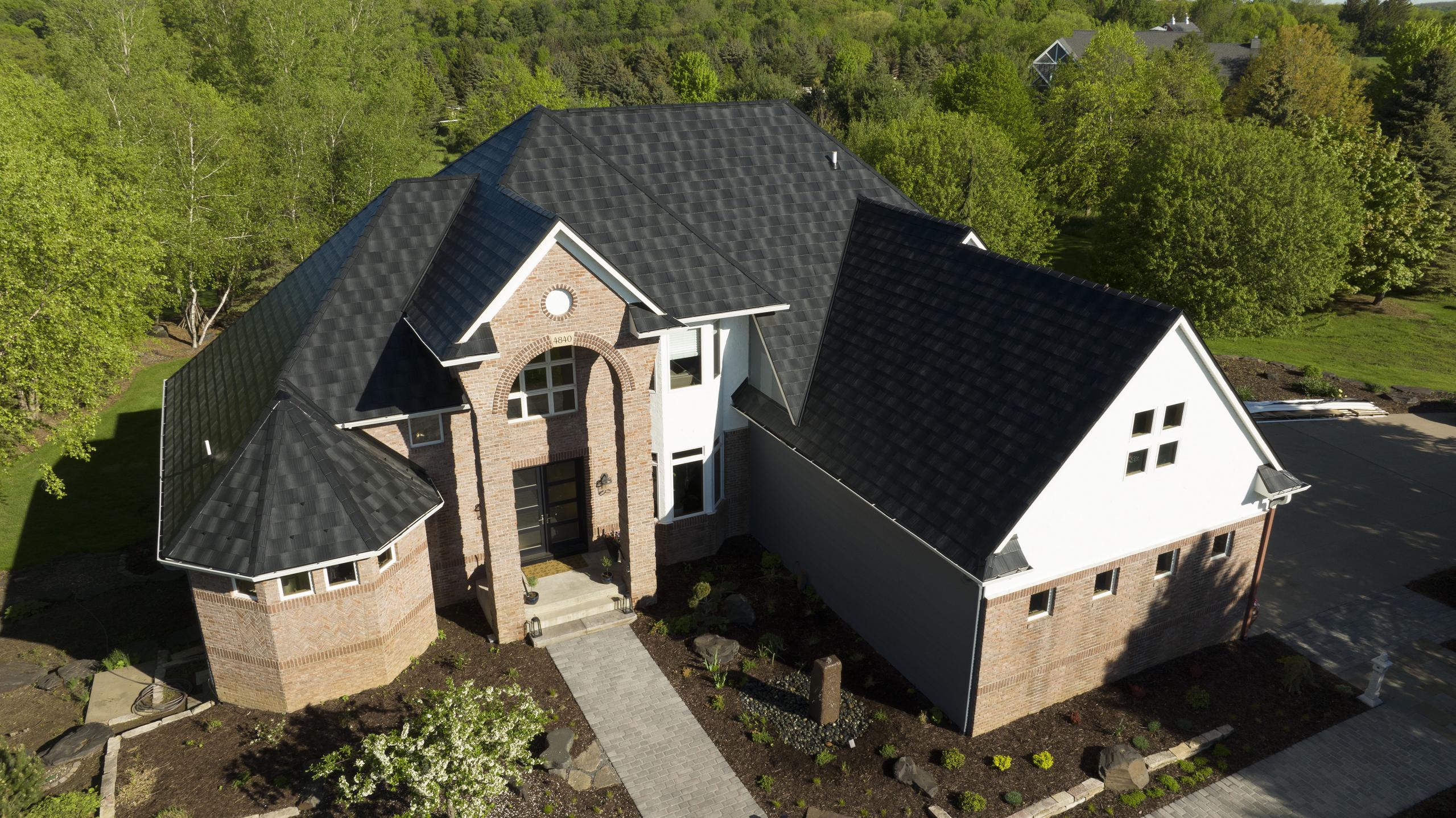 A brick home with Infiniti Textured Shake Metal Roofing in Obsidian, offering a sleek and durable contrast to the home’s classic design.