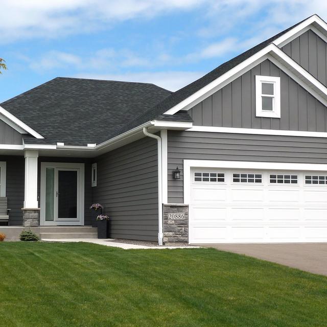 Suburban home with ArrowLine Slate steel roofing in Charcoal Gray, blending beautifully with the stone accents and lush green surroundings.
